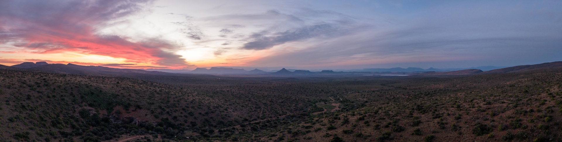 Sunset over a vast desert valley and distant mountains